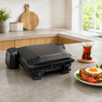 Gril électrique Tefal Toast Expert ouvert avec sandwichs gratinés sur table de petit-déjeuner